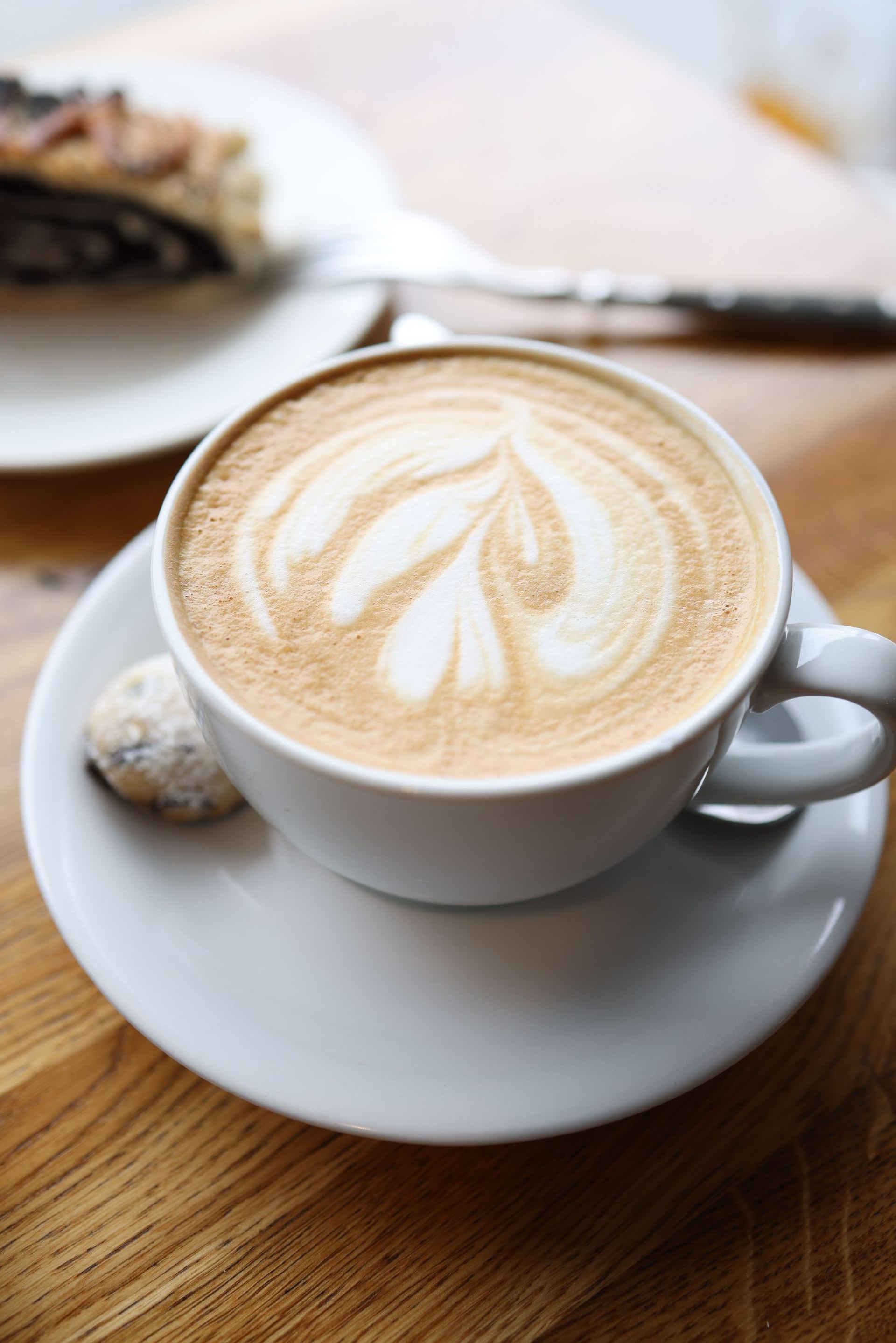 Cappuccino with latte art and a pastry on a café table
